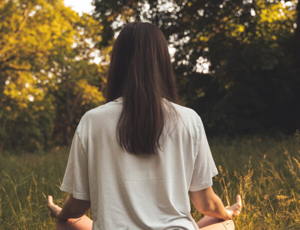 Meditation draußen sitzend Frau beim Meditieren Mantra Singen