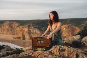 Bhakti Yogalehrerin an Klippen beim Mantra Singen auf Harmonium
